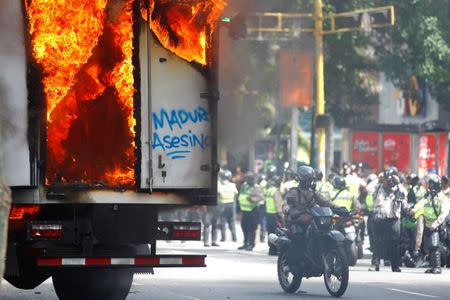 Riot security forces members congregate next to a government truck that was set on fire during a rally against Venezuelan President Nicolas Maduro's government in Caracas, Venezuela June 22, 2017. The graffiti reads "Maduro killer". REUTERS/Christian Veron TPX IMAGES OF THE DAY