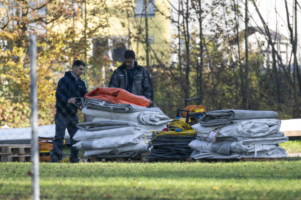 Two men dismantle tents tents that were set up as shelters for refugees in St. Georgen im Attergau, Austria, Monday, Nov. 14, 2022. In a weeks-long standoff with the Austrian government over the accommodation of rising numbers of asylum seekers in the alpine country, the mayor of the small village St. Georgen defied national housing measures and ordered the dismantling of more than a dozen tents for some 100 migrants in his community citing security concerns. (AP Photo/Andreas Schaad)