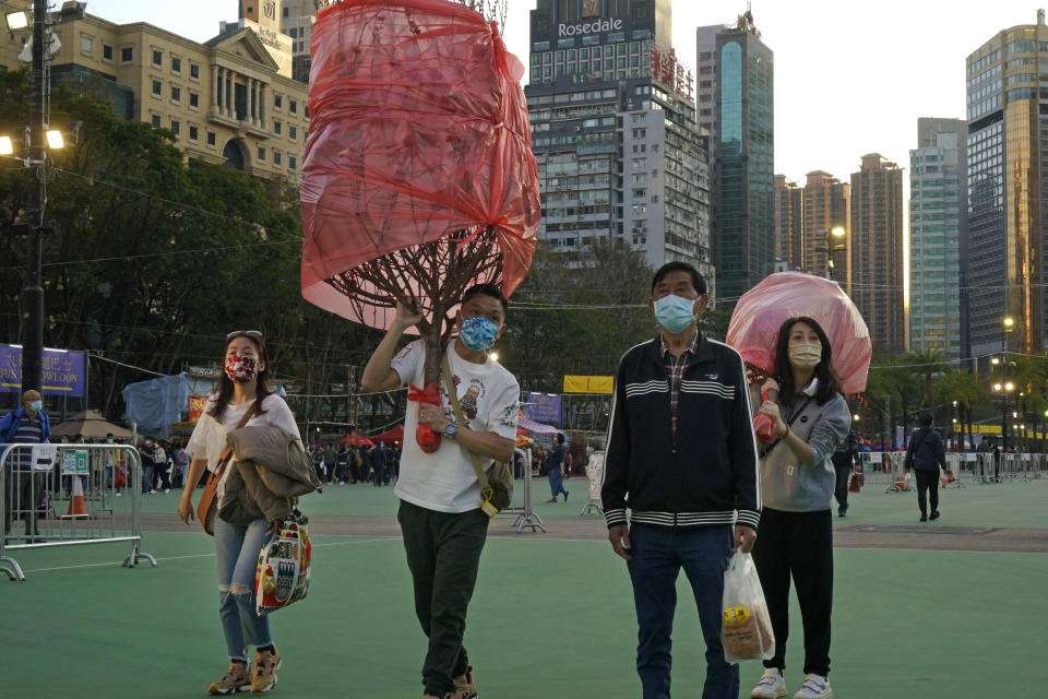 Customers wearing face masks to protect against the spread of the coronavirus, carry peach blossom trees at the flower markets in Victoria Park of Hong Kong, Saturday, Feb. 6, 2021. Traditional Lunar New Year flower markets opened Saturday in Hong Kong, after a government virus policy U-turn. At the biggest venue, Victoria Park next to the popular downtown shopping district of Causeway Bay, the eerie emptiness is in stark contrast to the usual bustle of capacity crowds.(AP Photo/Kin Cheung)