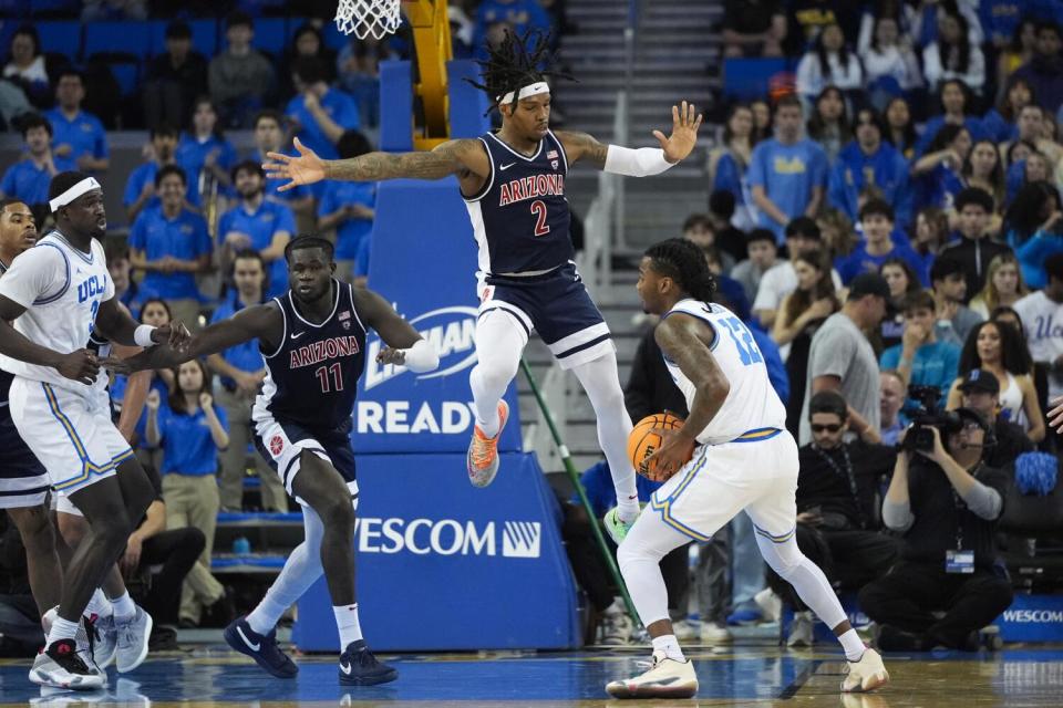 UCLA guard Sebastian Mack, right, looks to pass the ball.