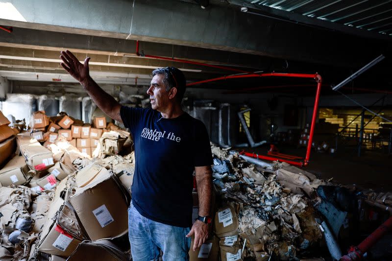 Avi Barssessat, CEO of Hollandia International, gestures towards where a rocket that was launched from the Gaza Strip struck and damaged his warehouse facility in Sderot