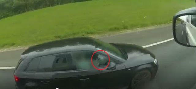 A driver using her phone and looking at her laptop while travelling on the M40