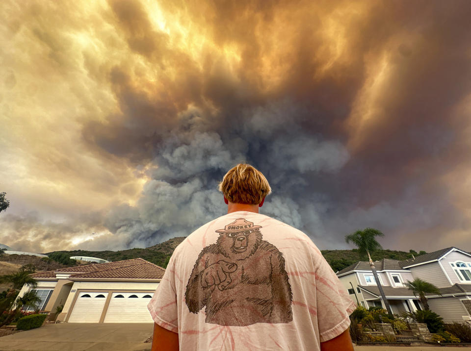 Aidan Thomas wears a Smokey Bear t-shirt as he watches smoke from the Airport Fire rise behind Meander Lane in Trabuco Canyon, Calif., on Monday, Sept. 9, 2024. (Jeff Gritchen/The Orange County Register via AP)