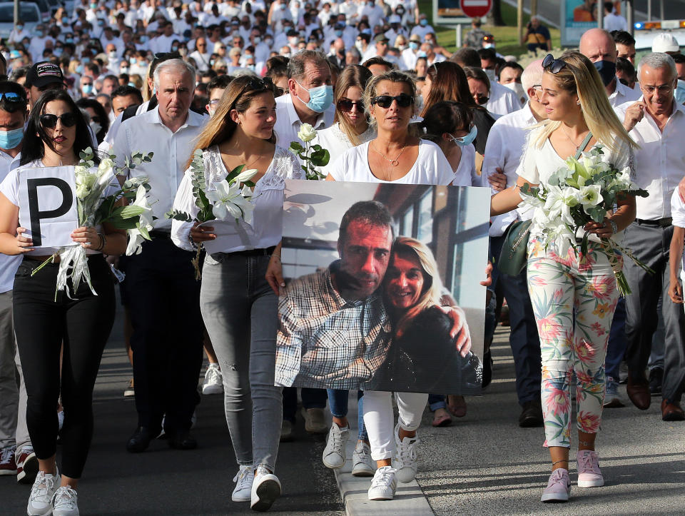 This July 8, 2020 file photo shows Veronique Monguillot, wife of Philippe Monguillot, a bus driver who was attacked in Bayonne on Sunday night, holding a photo of her with her husband, during a protest march in Bayonne, southwestern France. The wife of a French bus driver savagely beaten after he asked four of his passengers to wear face masks aboard his vehicle called Saturday for "exemplary punishment" after he died of his injuries. (AP Photo/Bob Edme)