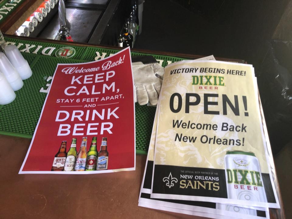 In this Friday, June 12, 2020 photo, stacks of signs for welcoming back patrons sit on the bar at Lafitte's Blacksmith Shop Bar on Bourbon Street in New Orleans. The city is allowing bars to open – with limited capacity and without live music – on Saturday. Bars were among the businesses shut down in mid-March as coronavirus infections increased in New Orleans and Louisiana became a hot spot for the disease. (AP Photo/Kevin McGill)