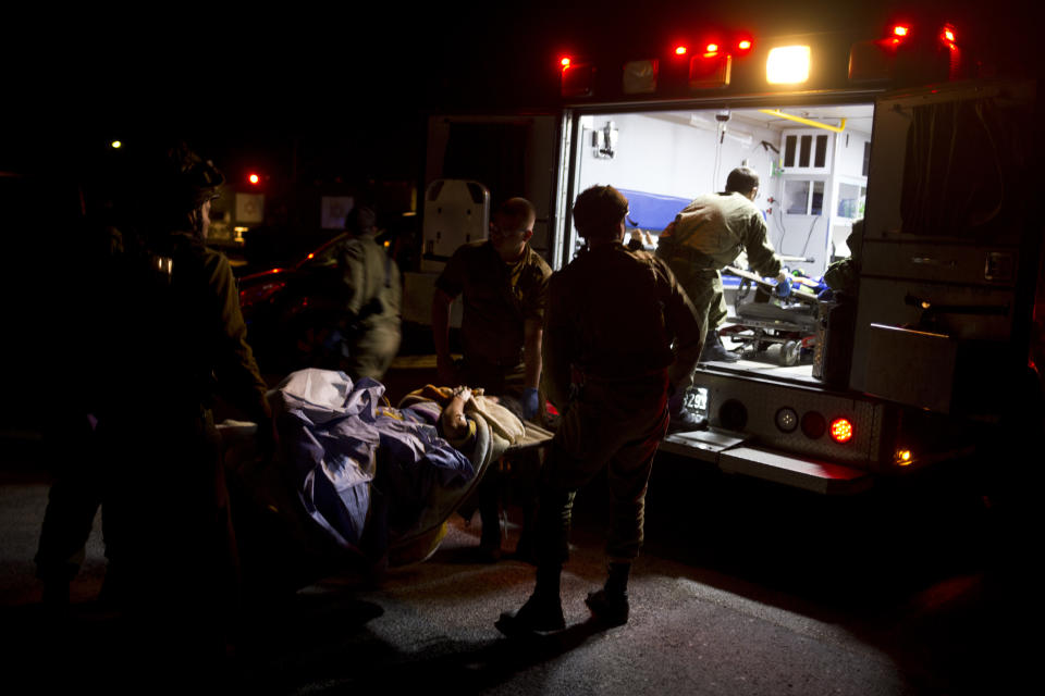 In this Thursday, April 6, 2017 photo made in Israeli controlled Golan Heights, Israeli military medics assist wounded Syrians. Seven wounded Syrians crossed into Israeli controlled Heights Thursday night have received immediate treatment and were hospitalized later on. They are the latest group of Syrians receiving free medical care through an Israeli military program operating since 2013. (AP Photo/Dusan Vranic)