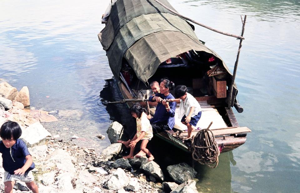 An elderly lady helps children to get ashore from a sampan in Hong Kong.