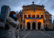 A woman wears a face mask as she walks by the Old Opera in Frankfurt, Germany, Thursday, Oct. 8, 2020. (AP Photo/Michael Probst)