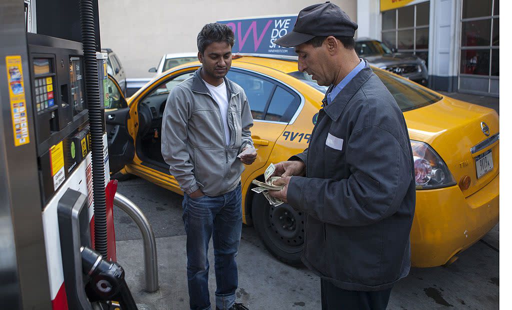 An employee of the Shell Station takes cash from a taxi driver for gas