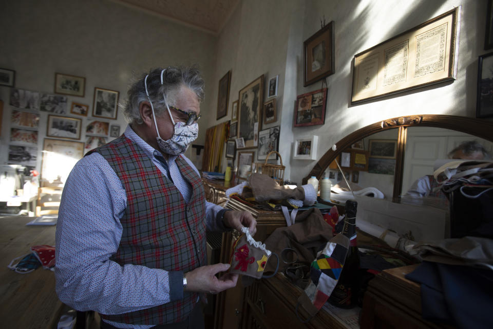 Tailor Karl Kersten holds a protective face mask in the tradition of the Gilles de Binche costume at his atelier in Binche, Belgium, Thursday, Feb. 11, 2021. The economic impact of the cancellation of this years carnival due to COVID-19 will be difficult for local craftspersons who rely on the income. Kersten, a fourth-generation tailor of Gilles de Binche costumes, spends all year preparing for the event and rents about 1,000 costumes. This year to pass the time he has been sewing masks to protect against the virus. (AP Photo/Virginia Mayo)
