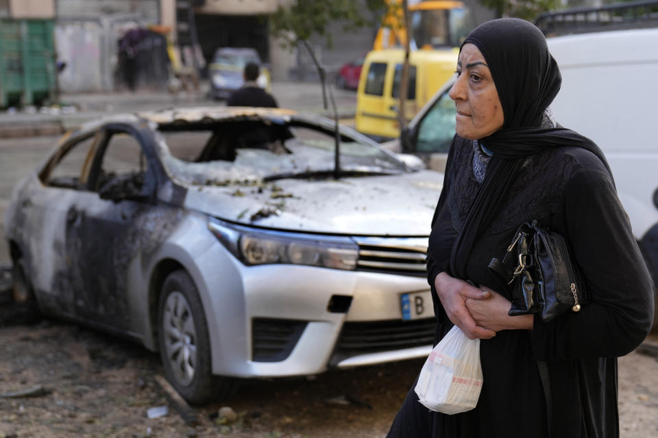 A Lebanese woman passes next of a burned car, near an apartment building where an apparent Israeli strike Tuesday killed top Hamas political leader Saleh Arouri, in the southern suburb of Beirut that is a Hezbollah stronghold, Lebanon, Wednesday, Jan. 3, 2024. The apparent Israeli strike that killed Hamas' No. 2 political leader, marking a potentially significant escalation of Israel's war against the militant group and heightening the risk of a wider Middle East conflict. (AP Photo/Hussein Malla)