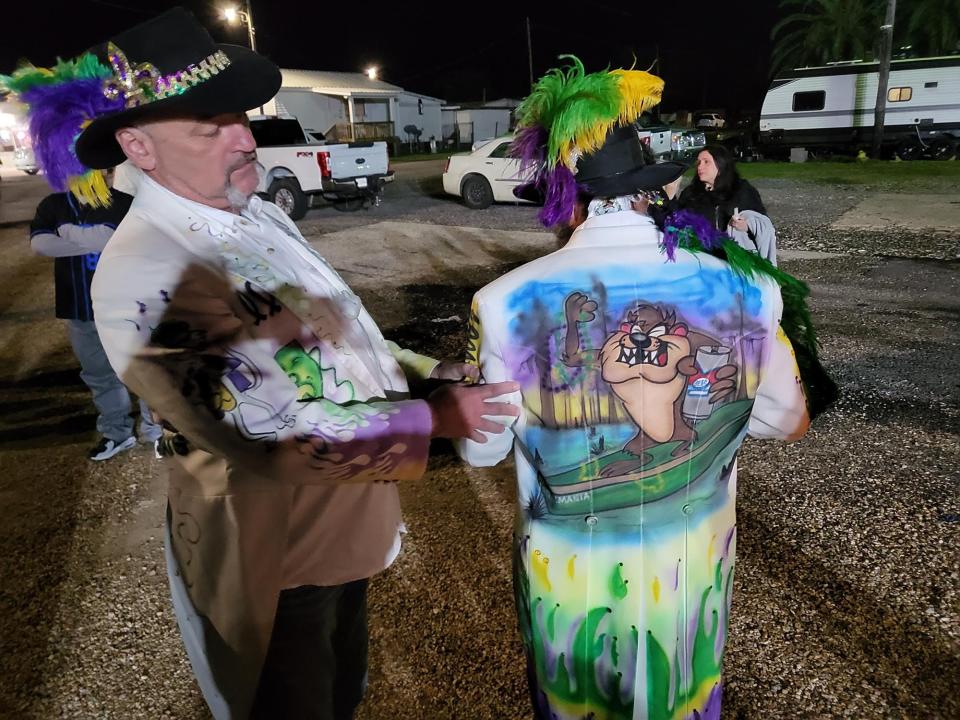 Joe Langley and Phil Cohn, members of the Selucrey Sophistocats Mardi Gras marching club, show a coat painted by Thomas Phillips, a Dulac native who went missing off a tugboat last week off Texas near the Louisiana border. Langley and Cohn were attending a candlelight vigil Monday night for Phillips, whose body was found the next morning.