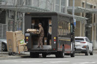 FILE - In this Thursday, March 26, 2020 file photo, a United Parcel Service driver loads boxes during a delivery in downtown Seattle. Amid the coronavirus outbreak, UPS and FedEx have stopped requiring signatures for packages. (AP Photo/Ted S. Warren)