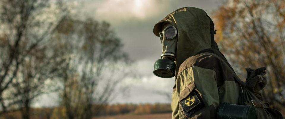 Man in gas mask turns to the camera.