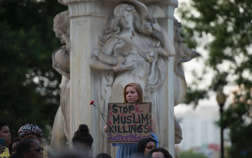 People hold up signs during a vigil in Washington, D.C.