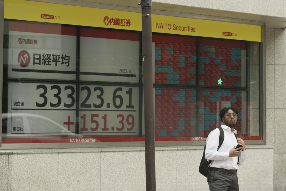 A man waits at an intersection near monitors showing Japan's Nikkei 225 index at a securities firm in Tokyo, Tuesday, Aug. 1, 2023. Asian shares mostly rose Tuesday, boosted by market optimism set off by a Wall Street rally despite lingering worries about inflation and regional growth. (AP Photo/Hiro Komae)
