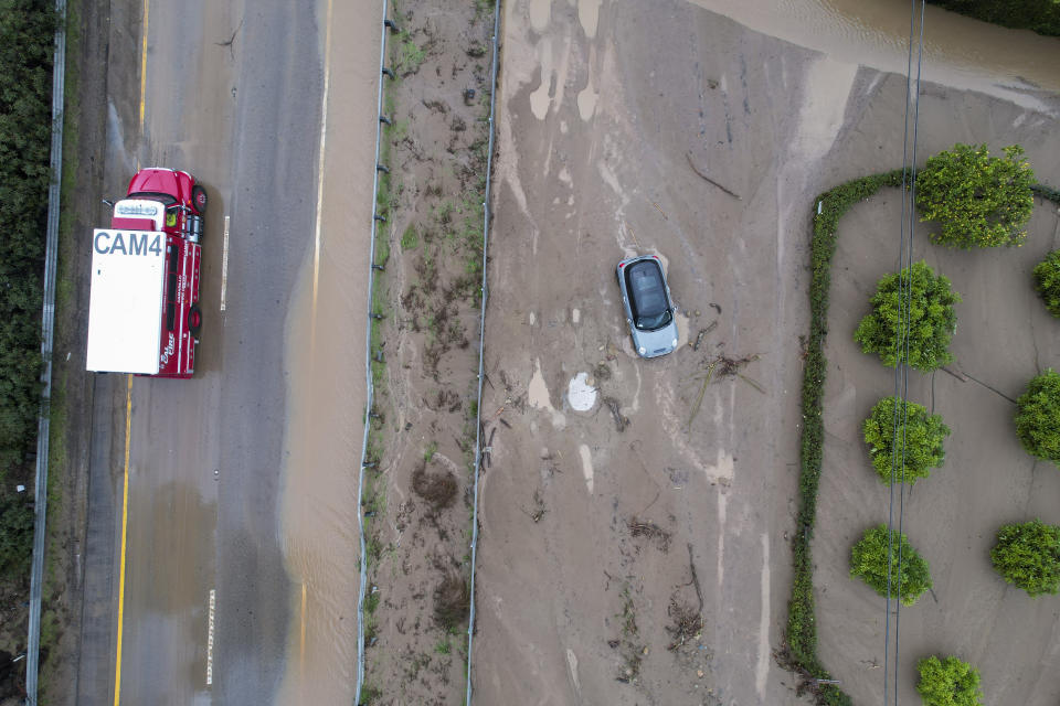 In an aerial view, A fire truck, left, passes by as a vehicle is trapped by mud and debris at Jameson Lane near Highway 101 in Montecito, Calif., Tuesday, Jan. 10, 2023. California saw little relief from drenching rains Tuesday as the latest in a relentless string of storms swamped roads, turned rivers into gushing flood zones and forced thousands of people to flee from towns with histories of deadly mudslides. (AP Photo/Ringo H.W. Chiu)