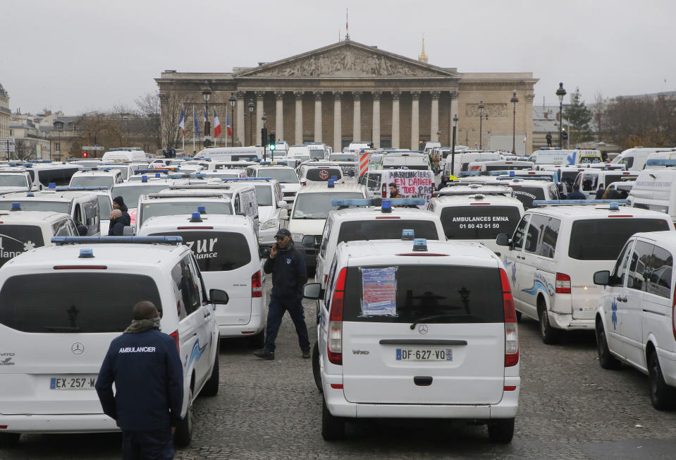 Ambulance workers block the bridge leading the National Assembly, background, in Paris, Monday, Dec. 3, 2018. Ambulance workers took to the streets and gathered close to the National Assembly in downtown Paris to complain about changes to working conditions as French Prime Minister Edouard Philippe is holding crisis talks with representatives of major political parties in the wake of violent anti-government protests that have rocked Paris. (AP Photo/Michel Euler)