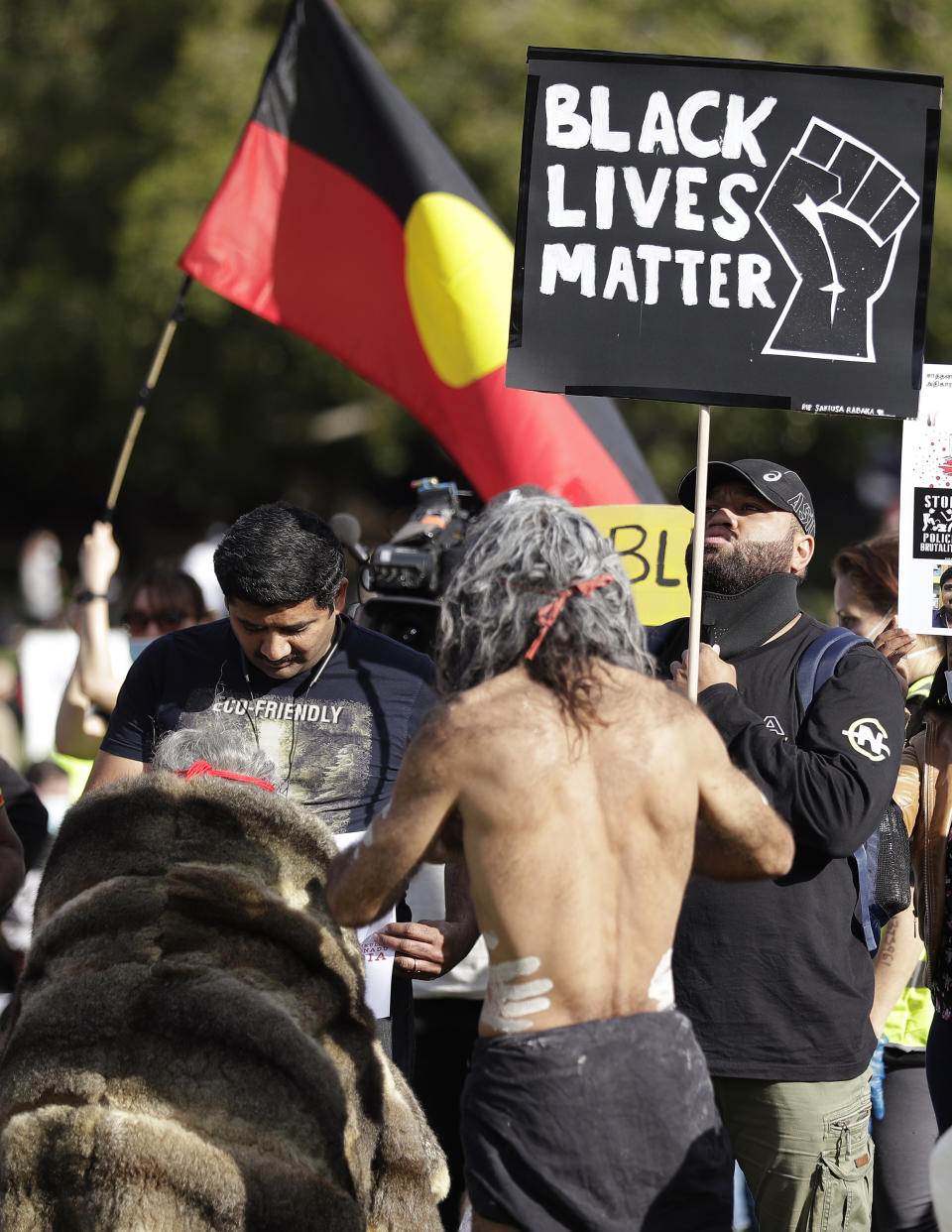 Aboriginal elders carry a small fire during a traditional smoking ceremony as thousands gather at a rally supporting the Black Lives Matter and Black Deaths in Custody movements in Sydney, Sunday, July 5, 2020. (AP Photo/Rick Rycroft)