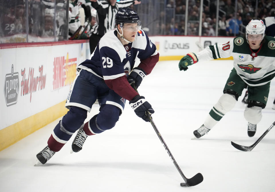 Colorado Avalanche center Nathan MacKinnon, left, drives to the net as Minnesota Wild center Oskar Sundqvist pursues in the third period of an NHL hockey game Wednesday, March 29, 2023, in Denver. (AP Photo/David Zalubowski)
