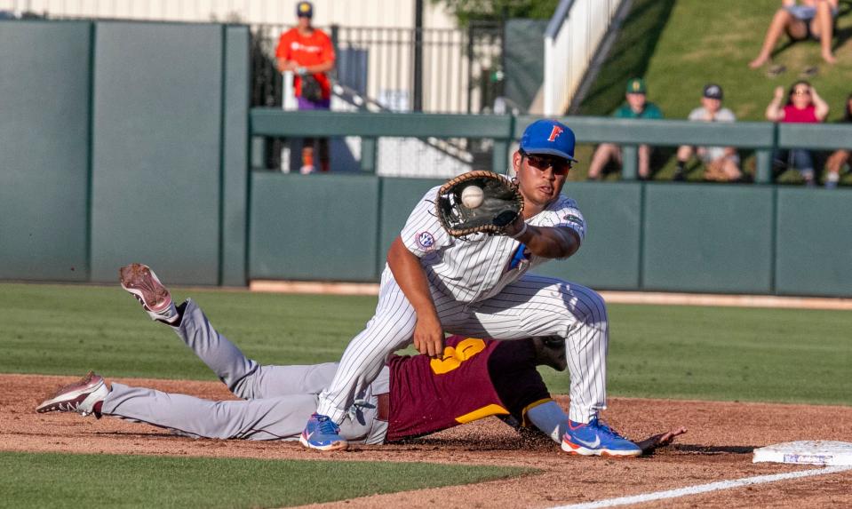 Florida's Kendrick Calilao gets the throw to first as Central Michigan's Jacob Donahue dives back during an NCAA baseball tournament regional game Friday, June 3, 2022, in Gainesville, Fla.