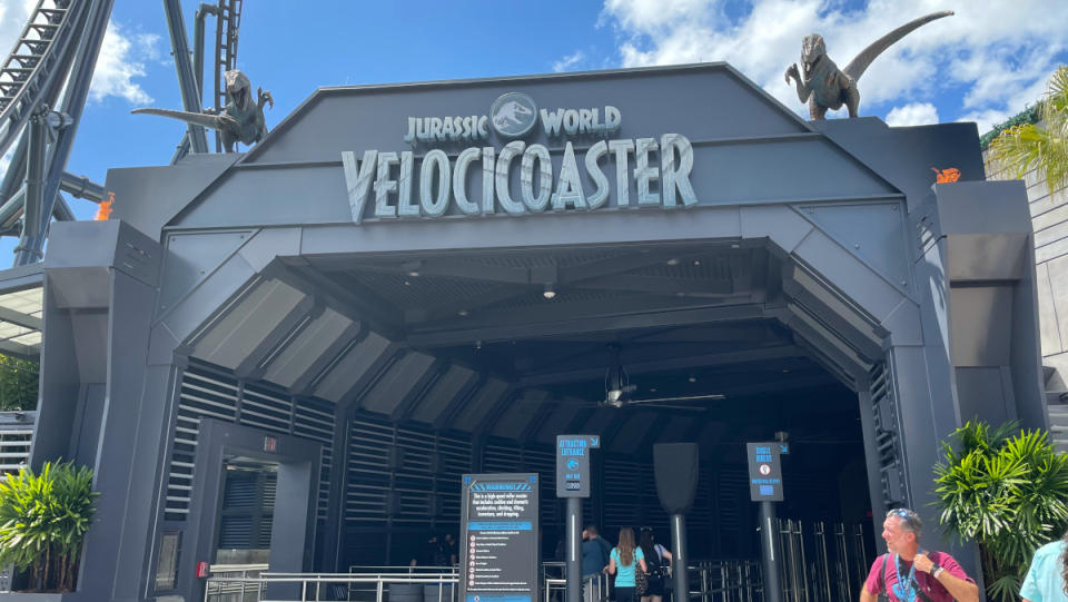 The gray entrance of the VelociCoaster, flanked by two raptor statues