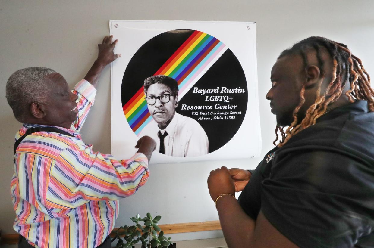 Steve Arrington, chief administrator of the Bayard Rustin LGBTQ Resource Center/Akron AIDS Collaborative and Gregory Price, Northeast associate director of clinical operations hang a banner in the lobby of the Rustin Center in Akron.