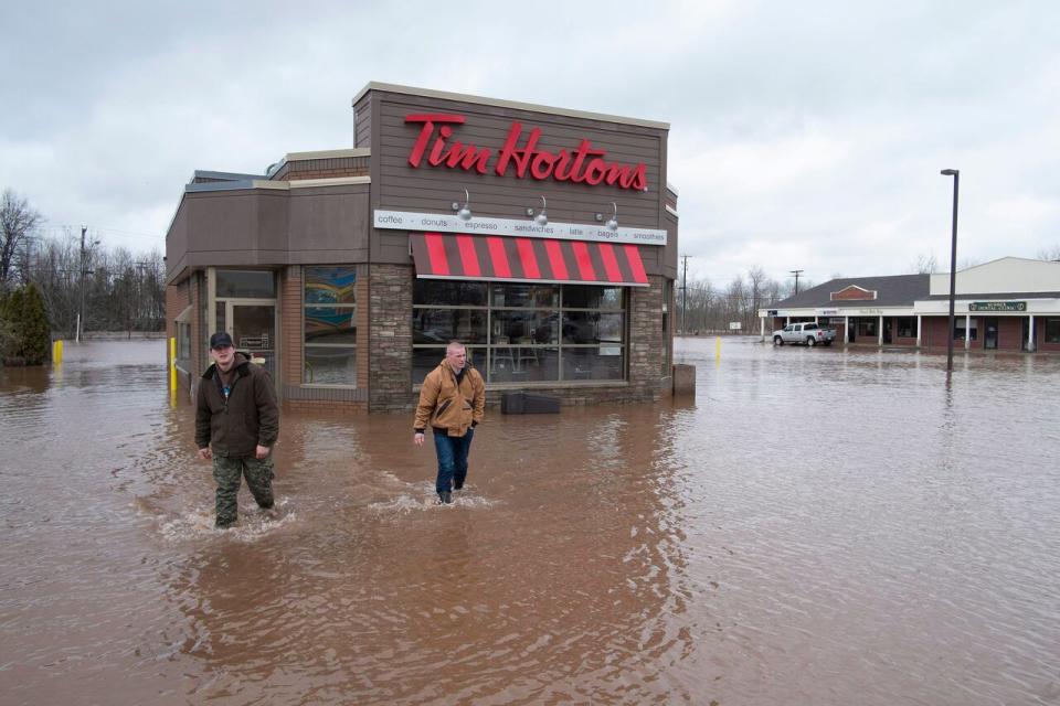 Keegan Worden, left, and David Clement check on a flooded Tim Horton's location along Main Street in Sussex, N.B., on April 16, 2014.