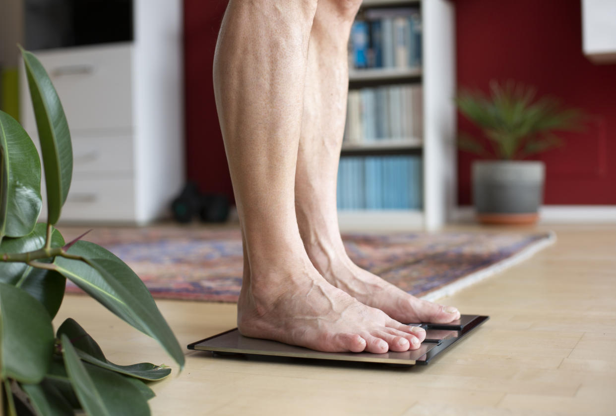 Man standing on weighing scales. (Getty Images)