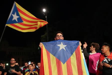 A man holds an Estelada (Catalan separatist flag) as people gather at Plaza Catalunya after voting ended for the banned independence referendum, in Barcelona, Spain October 1, 2017. REUTERS/Susana Vera
