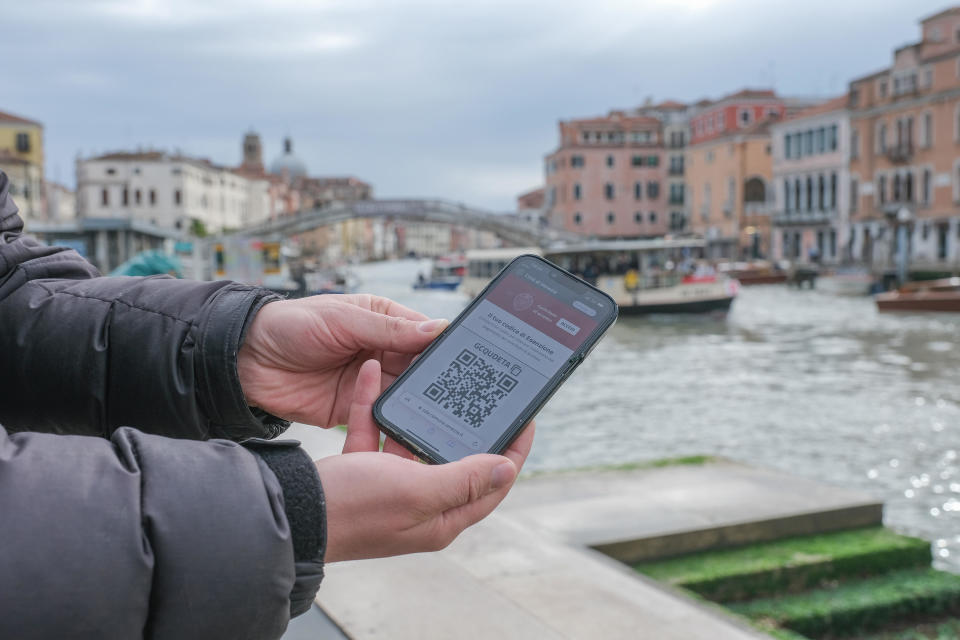 A tourist displays a QR code used to enter the Venice, Italy on the first day of a pilot program charging visitors a 5 Euro entry fee. / Credit: Getty Images