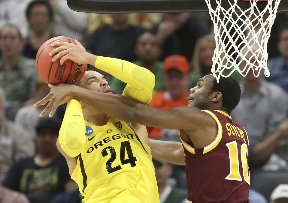 Oregon forward Dillon Brooks, left, goes to the basket against Iona guard Jon Severe, during the first half of a first-round game in the men's NCAA college basketball tournament in Sacramento, Calif., Friday, March 17, 2017. (AP Photo/Steve Yeater)