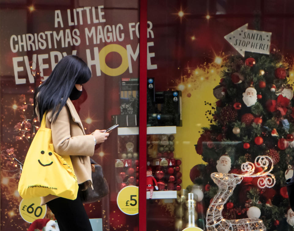 A woman walks past a Christmas display in a shop window in Leeds, Yorkshire, as England continues a four week national lockdown to curb the spread of coronavirus.