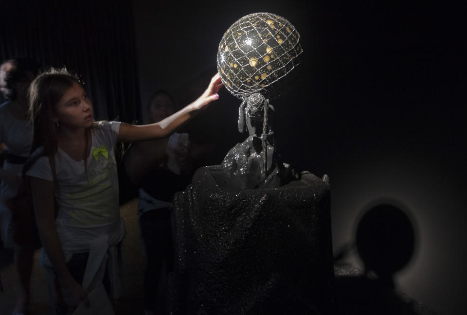 In this photo taken Wednesday, May 29, 2013, a visitor touches the sculpture 'The widow' inside the Canadian Pavilion displaying the installation 'Music for Silence' by artist Shary Boyle during a preview of the 55th edition of the Venice Biennale of Arts in Venice, northern Italy. (AP Photo/Domenico Stinellis)