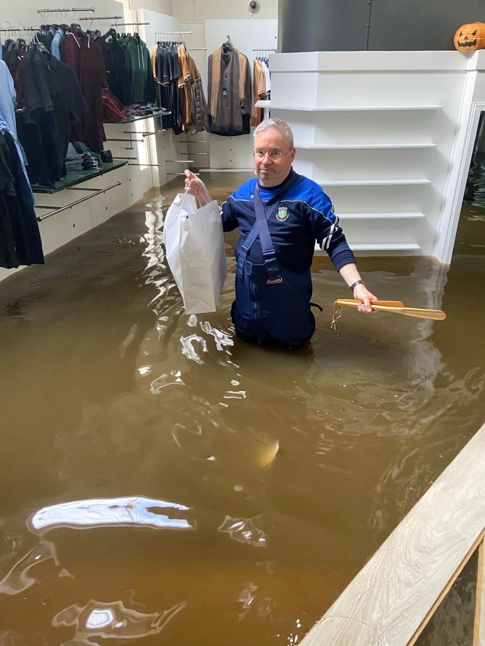 A business owner salvages stock from clothing shop McCartan Bros which was left in an ‘absolute mess’ by floodwater (PA)