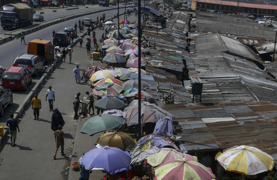 FILE - In this April 13, 2020, file photo, people shop at a roadside market with few customers in Lagos, Nigeria. Lockdowns in Africa limiting the movement of people in an attempt to slow the spread of the coronavirus are threatening to choke off supplies of what the continent needs the most: Food. (AP Photo/Sunday Alamba, File)