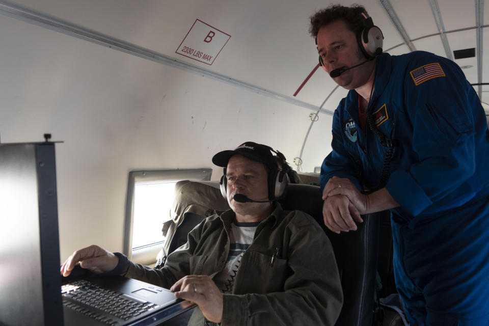 In this photo taken on Wednesday, Aug. 14, 2019, NASA project manager Ian McCubbin, left, and NASA scientist Josh Willis check data from a probe that they just dropped from a plane as they fly on a mission to track melting ice in eastern Greenland. Greenland has been melting faster in the last decade and this summer, it has seen two of the biggest melts on record since 2012. (AP Photo/Mstyslav Chernov)