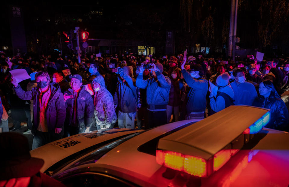 Protesters march by a police cruiser in Beijing. Source: Getty