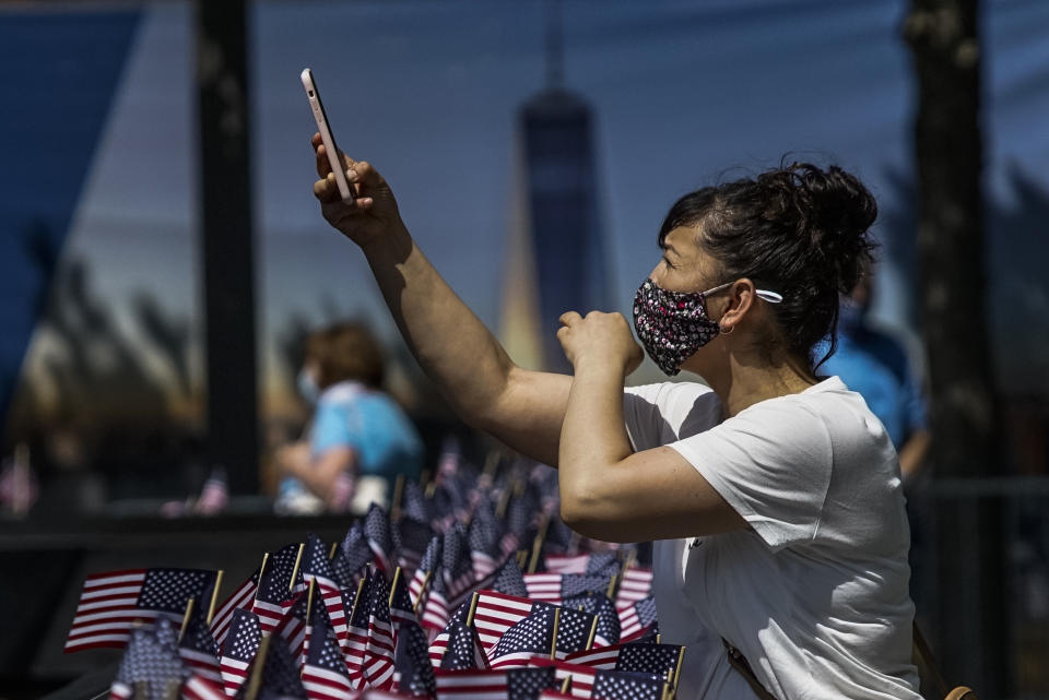 A woman takes pictures with her phone as people visit the 9/11 Memorial Plaza during its reopening after having been closed for more than three months amid the coronavirus pandemic, Saturday, July 4, 2020, in New York. (AP Photo/Eduardo Munoz Alvarez)