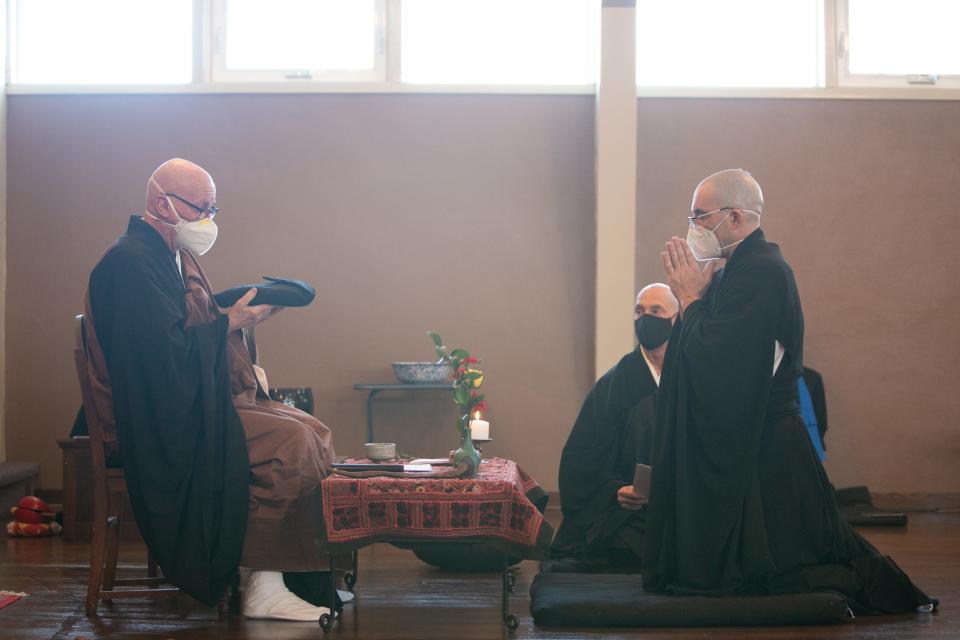 Head teacher, Rev. Eido Espe, offers Rev. Gendo Curt Thornberry "Buddha's robe" during the priest ordination ceremony at the Des Moines Zen Center in Des Moines, IA. The officiant presents the articles of ordination to the ordainee, who initially refuses them indicating he/she is not worthy of them, but which are eventually accepted. The robe was hand-sewn by the ordainee.