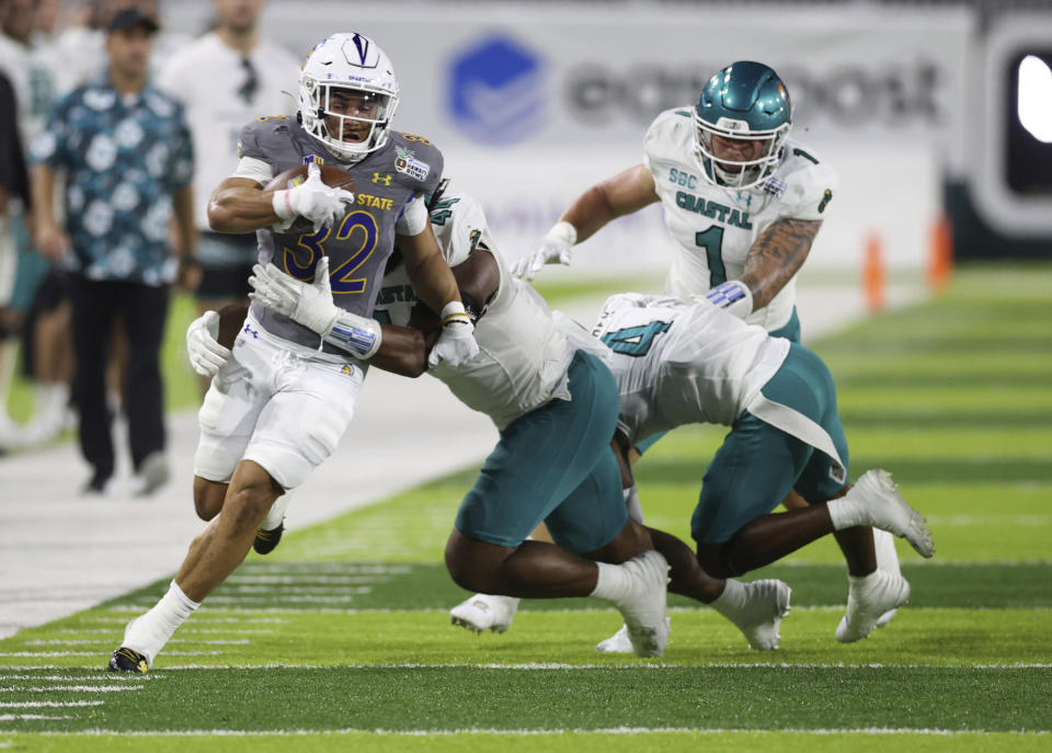 Coastal Carolina defensive lineman Will Whitson (44) tries to pull down San Jose State running back Kairee Robinson (32) during the first half of the Hawaii Bowl NCAA college football game Saturday, Dec. 23, 2023, in Honolulu. The play was negated by a penalty. (AP Photo/Marco Garcia)