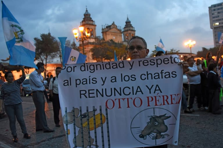 A man holds a sign reading: "Out of dignity and respect for the country resign now Otto Perez" as Guatemalans celebrate after Congress voted unanimously to strip the president of his immunity in Guatemala City on September 1, 2015