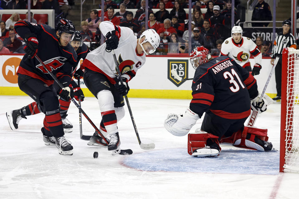 Ottawa Senators' Brady Tkachuk (7) works for the puck between Carolina Hurricanes' Frederik Andersen (31) and Brady Skjei (76) during the first period of an NHL hockey game in Raleigh, N.C., Wednesday, Oct. 11, 2023. (AP Photo/Karl B DeBlaker)