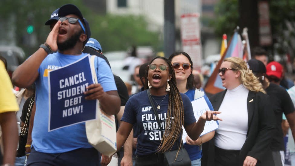 People holding 'cancel student debt now' signs