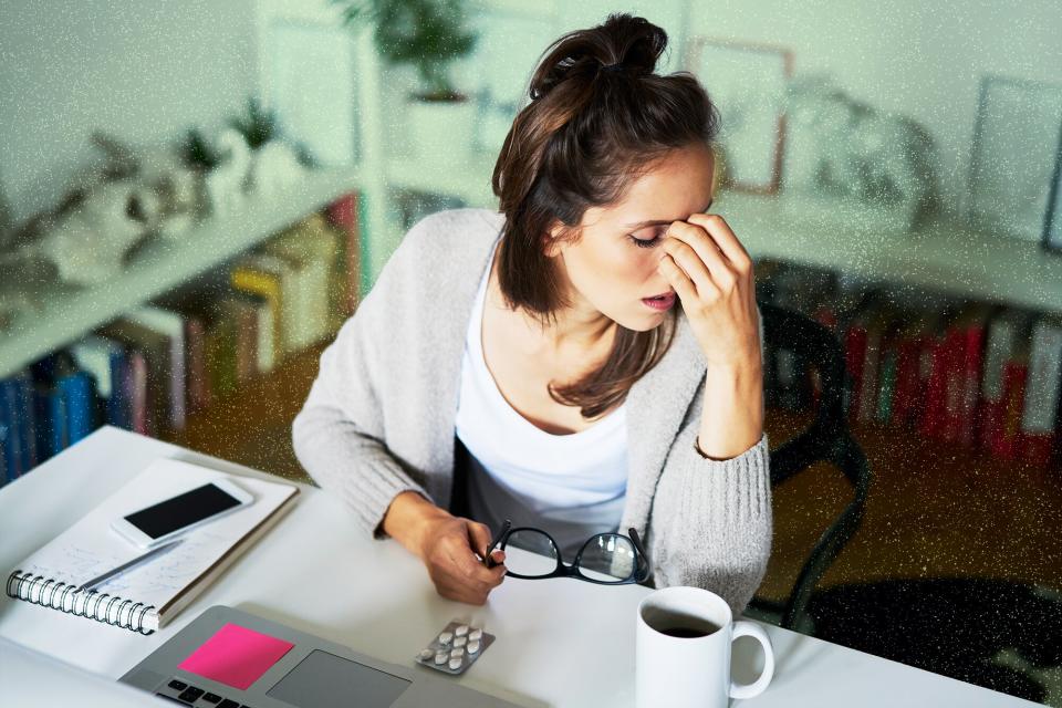 Young woman at home at desk suffering headache