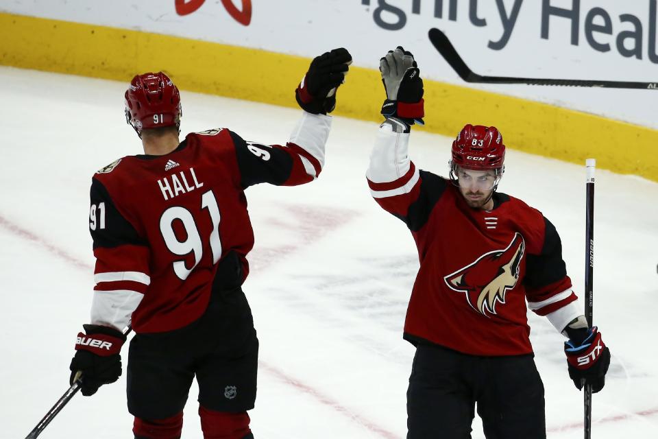 Arizona Coyotes right wing Conor Garland (83) celebrates his empty net goal against the San Jose Sharks with Coyotes left wing Taylor Hall (91) during the third period of an NHL hockey game Tuesday, Jan. 14, 2020, in Glendale, Ariz. The Coyotes defeated the Sharks 6-3. (AP Photo/Ross D. Franklin)