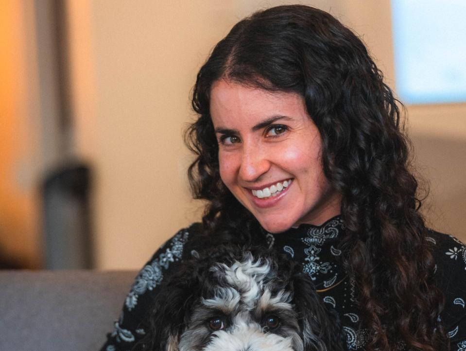 Morgan Beller, general partner at NFX, smiling with her fluffy dog, both sitting on a couch