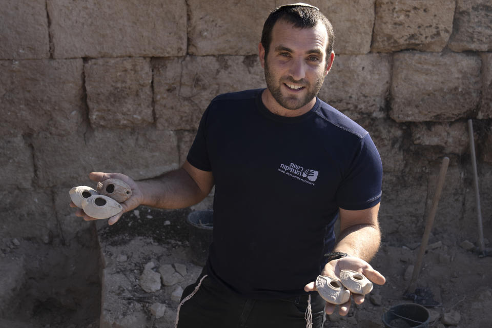 El arqueólogo Zvi Firer, de la Autoridad de Antigüedades de Israel, sostiene lámparas de arcilla encontradas en un sitio de 2000 años de antigüedad llamado la Cueva de Salomé, en el bosque de Lachish en Israel, el martes 20 de diciembre de 2022. (Foto AP/Maya Alleruzzo)