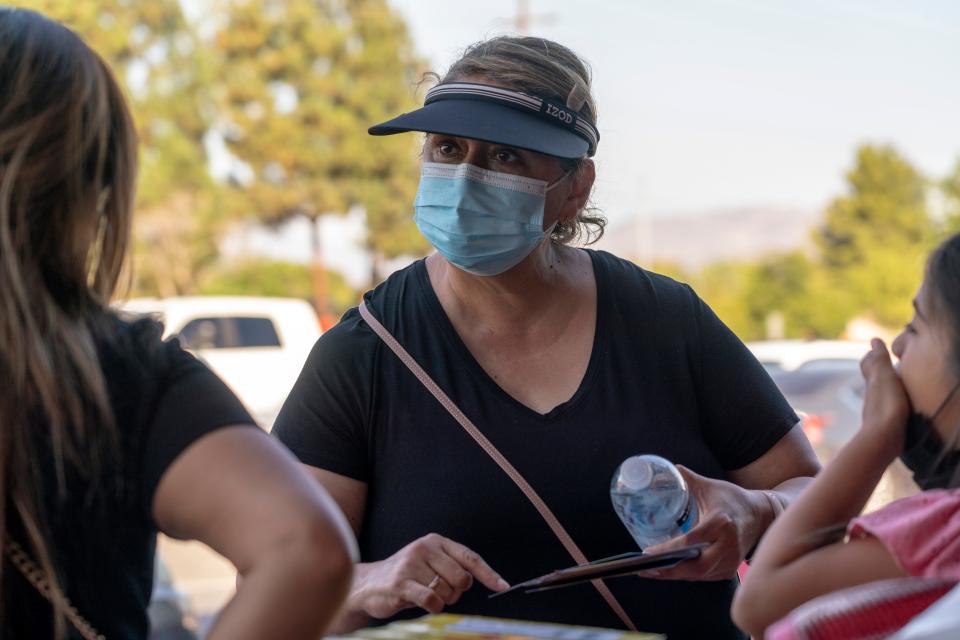 Hilda Martinez, a community organizer funded through Great Public Schools Now's L.A. Education Recovery Fund, hands out flyers about the Los Angeles Unified School District's requirements for students to return to in-person classes outside a Target store in Pacoima, California on Aug. 10, 2021.