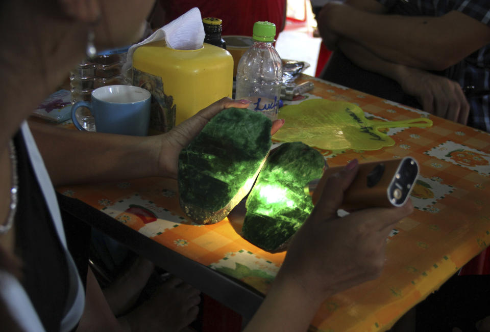 FILE - In this Sept. 18, 2015, file photo, local people examine the quality of a jade stone in the Hpakant area of Kachin state, northern Myanmar. A report by the independent research group Global Witness says Myanmar’s Feb. 1 military takeover has crushed prospects for better safety and environmental controls in its lucrative but conflict-ridden jade mining sector. (AP Photo/Esther Htusan, File)